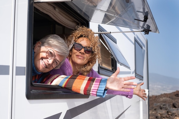 Deux femmes heureuses voyageant dans un camping-car regardant par la fenêtre en train de voyager