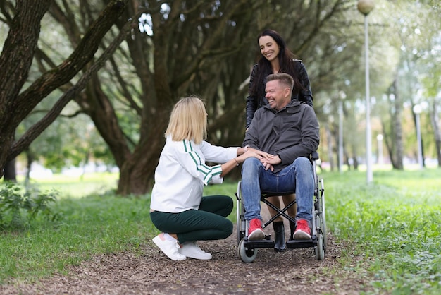 Deux femmes et un homme en fauteuil roulant parlent dans la réhabilitation du parc après des blessures et de l'aide