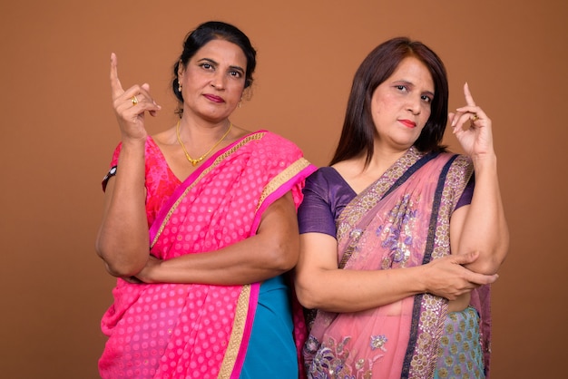 Deux femmes indiennes matures portant des vêtements traditionnels indiens Sari ensemble pointant