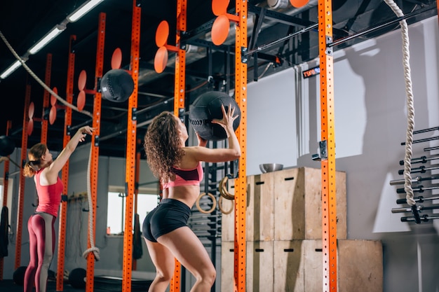 Deux femmes jette des boules de médecine dans la salle de fitness