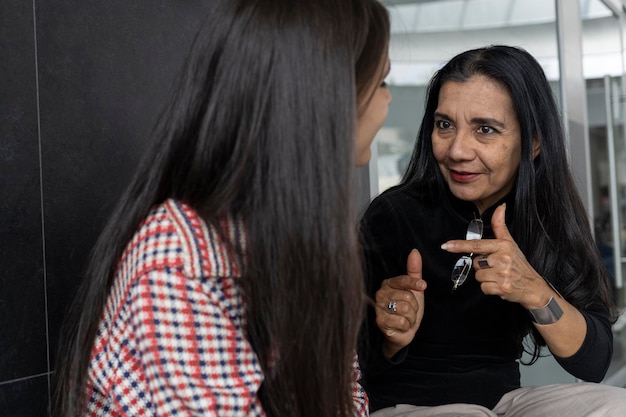 Deux femmes latino-américaines mère et fille assises et parlant Concept relations familiales