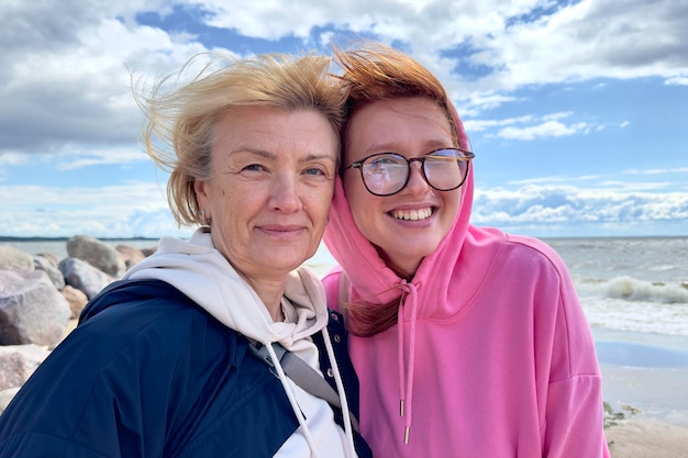 Deux femmes marchent sur la plage et sourient