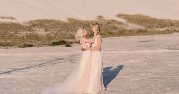 Deux femmes mariées en robe blanche aux cheveux blonds s'embrassant, mariage lesbien