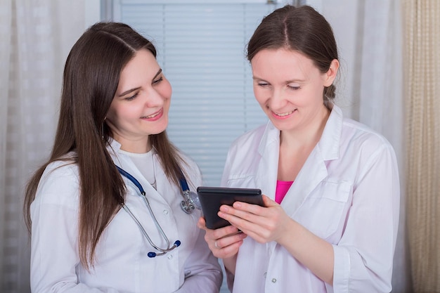 Deux femmes médecins ou infirmières regardent la tablette et discutent de la thérapie