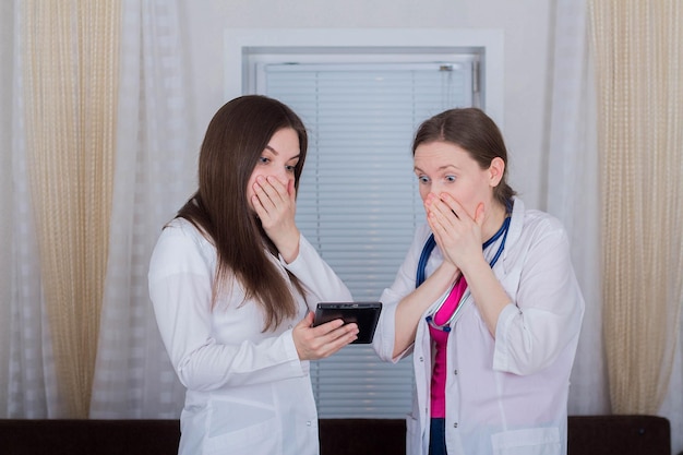 Deux femmes médecins ou infirmières regardent la tablette une est choquée ou très surprise