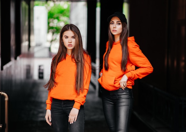 Deux femmes à la mode en pull orange posant.