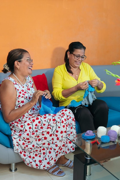 Deux femmes mûres tricotant une écharpe ensemble à la maison