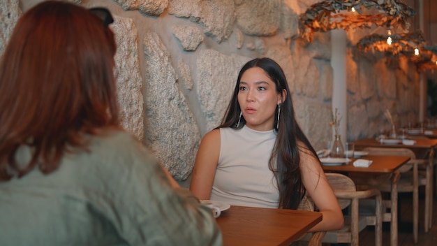 Deux femmes parlent à la cafétéria. Une belle fille asiatique bavardant avec un ami.