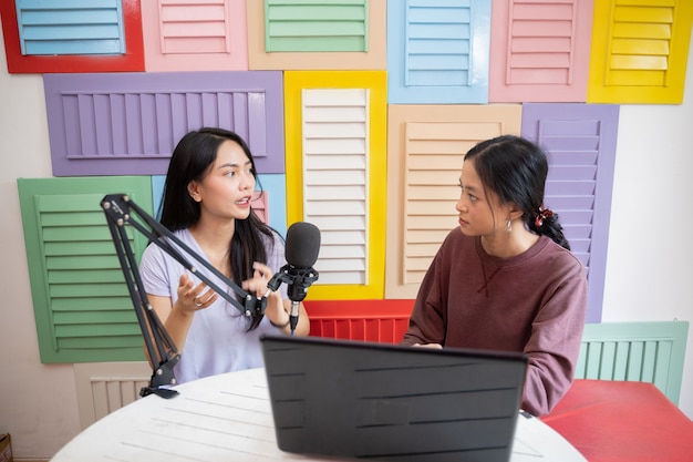 Deux femmes parlent sérieusement et utilisent des microphones pendant l'enregistrement d'un podcast