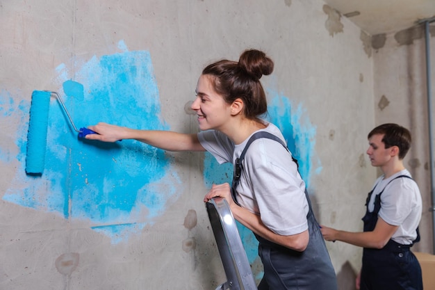 Deux femmes peignant un mur avec de la peinture bleue