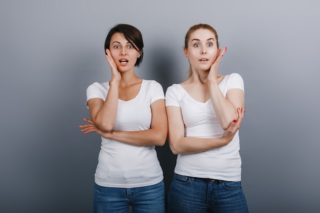 Deux femmes posant dans le studio se croisèrent les mains et se touchaient le visage en disant.