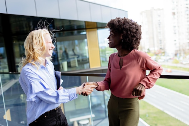 Photo deux femmes professionnelles partagent une conversation joyeuse dans un immeuble de bureaux moderne