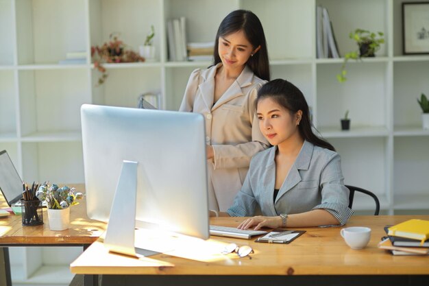 Deux femmes responsables marketing professionnelles regardant un écran d'ordinateur pc vérifiant les détails ensemble