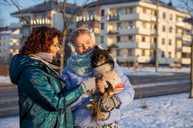 Photo deux femmes s'occupent d'un petit chien à l'extérieur.