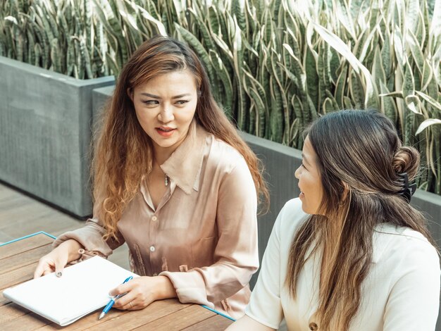 deux femmes sont assises à une table et l'une a une chemise blanche sur elle