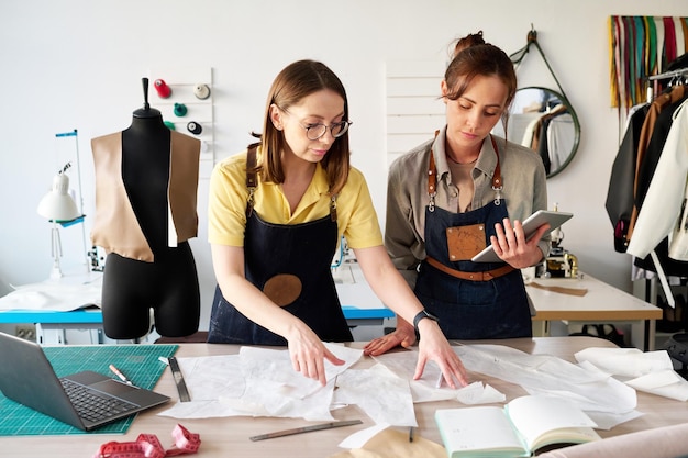 Deux femmes tailleurs choisissant des patrons de papier à coudre par lieu de travail en studio
