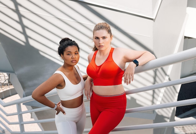 Deux femmes en tenue de fitness debout sur les escaliers d'un pont et regardant la caméra