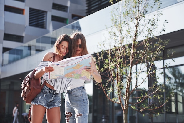 Deux femmes touriste avec carte visitant une nouvelle ville et cherchant un moyen de se rendre à l'hôtel.