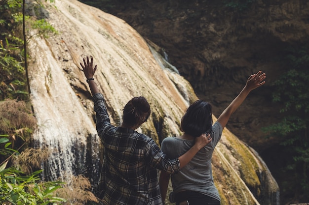 Deux femmes de touristes levant la main et devant une belle cascade