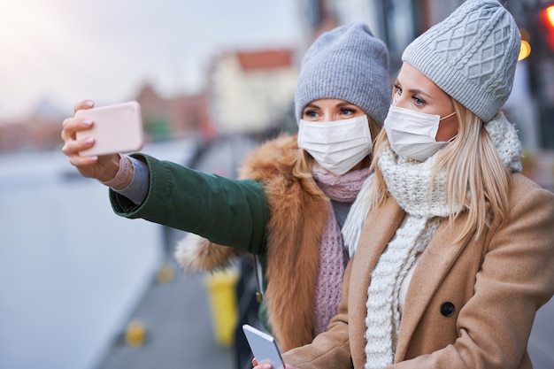 deux femmes utilisant des smartphones et portant des masques dans la ville