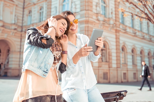 Deux femmes utilisant une tablette ensemble dans la rue de la ville