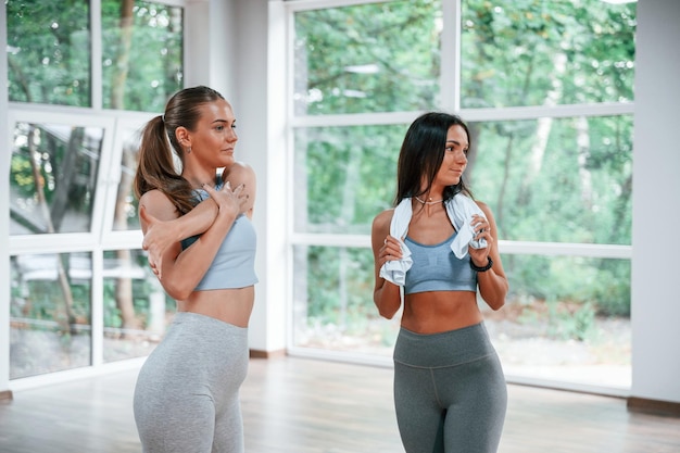 Deux femmes en vêtements sportifs debout ensemble dans la salle de gym