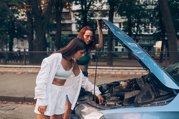 Deux femmes avec une voiture cassée sur la route Capot ouvert