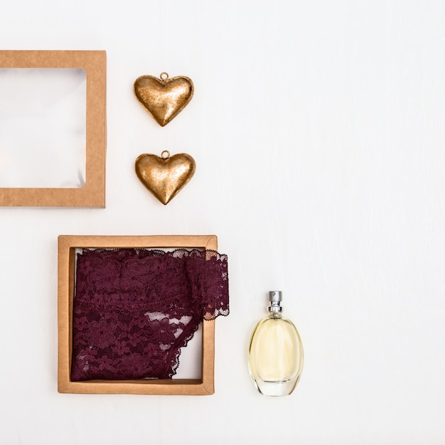 Deux figures de coeur, parfum, sous-vêtements féminins, boîte en papier cadeau. Concept de fond de Saint Valentin. Vue de dessus. Mise à plat.