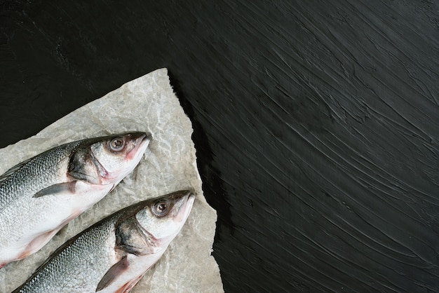 Deux filet de poisson cru aux épices, herbes, citron et sel sur fond de pierre noire