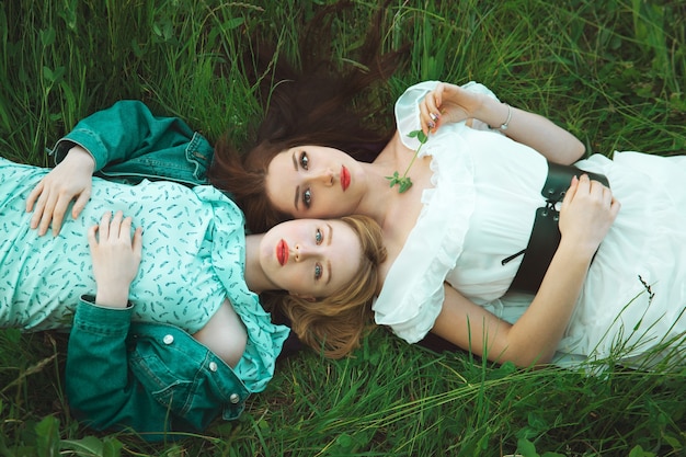 Deux fille romantique allongée sur la prairie d'herbe. Vue de dessus. Flou artistique. Concept de liberté et de jeunesse