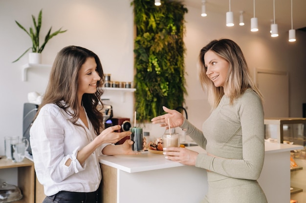 Deux filles à l'allure sportive avec des cocktails à la main discutent d'une alimentation et d'un régime sains