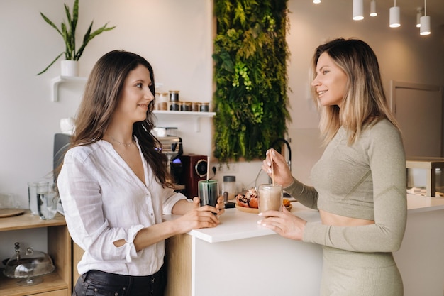 Deux filles à l'allure sportive avec des cocktails à la main discutent d'une alimentation et d'un régime sains