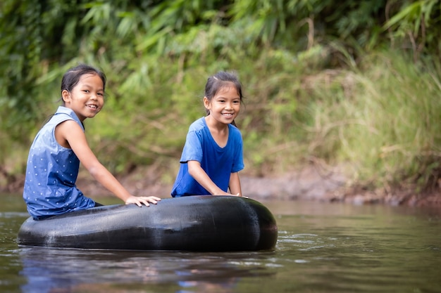 Deux filles asiatiques enfant assis sur un anneau en caoutchouc et jouer ensemble dans la rivière