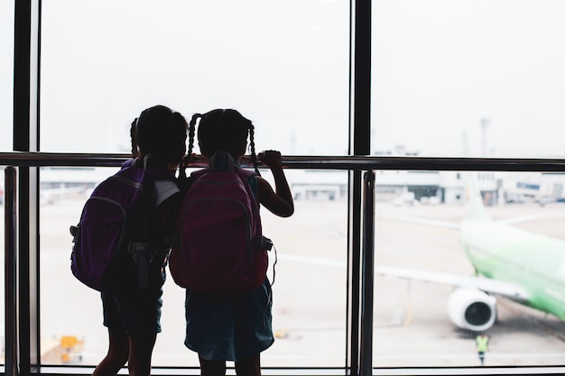 deux, filles asiatiques, enfant, à, sac à dos, regarder avion, et, embarquement, dans, aéroport