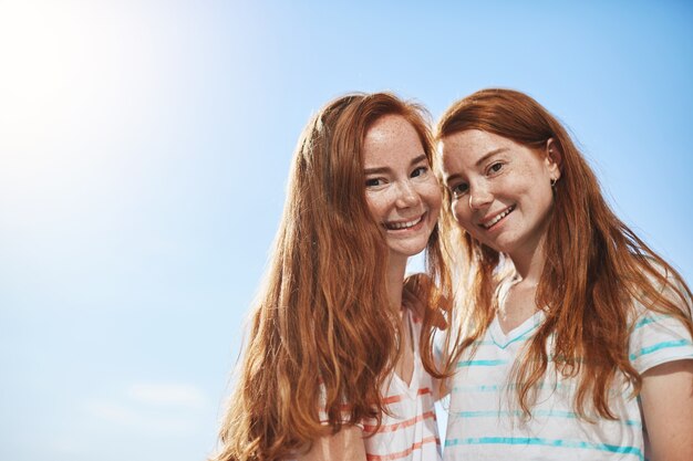 Deux filles au gingembre souriant sur une journée d'été ensoleillée. Avoir une sœur jumelle est une grande chance.