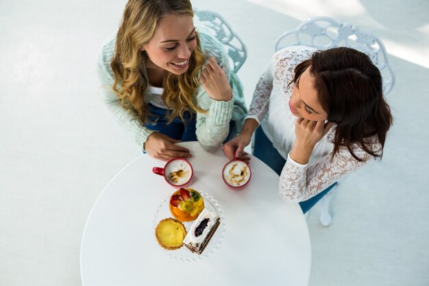 deux filles boivent du café et mangent des pâtisseries