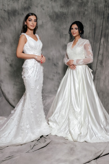 Deux filles dans un portrait de studio de robe de mariée sur fond gris