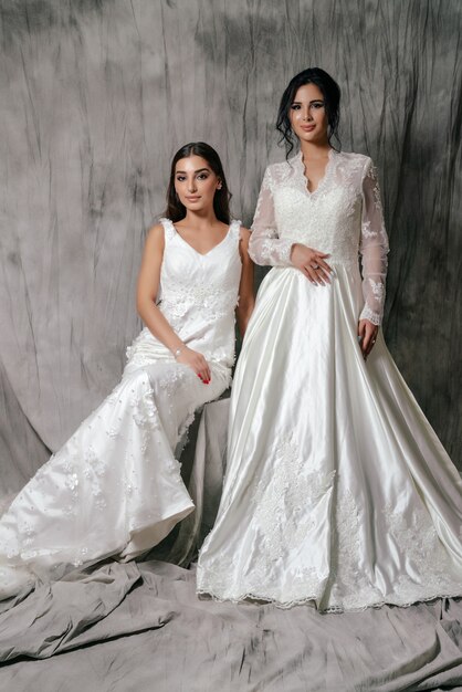 Deux filles dans un portrait de studio de robe de mariée sur fond gris