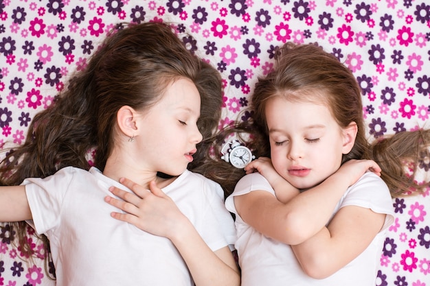 Deux filles endormies et un réveil blanc