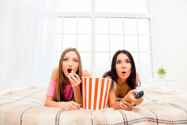 Deux filles excitées regardant un film et mangeant du pop-corn