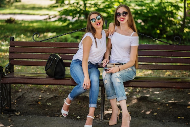 Deux filles fabuleuses s'asseyant sur le banc en parc