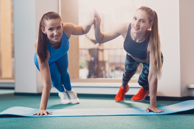 Photo deux filles heureuse effectuent des exercices sportifs à l'entraînement