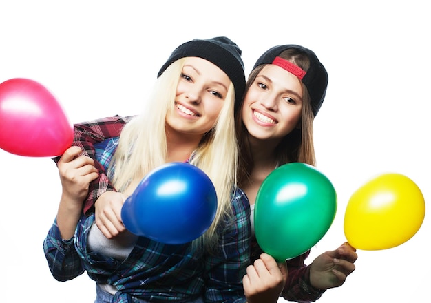 Deux filles hipster heureux souriant et tenant des ballons colorés sur fond blanc