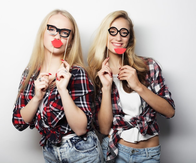 Deux filles hipster sexy et élégantes meilleures amies prêtes pour la fête, sur fond gris