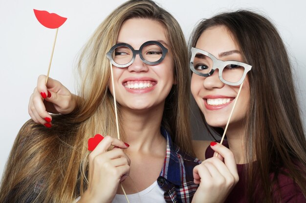 Deux filles hipster sexy et élégantes meilleures amies prêtes pour la fête, sur fond gris