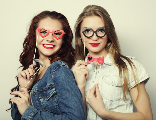 Deux filles hipster sexy et élégantes meilleures amies prêtes pour la fête, sur une surface grise