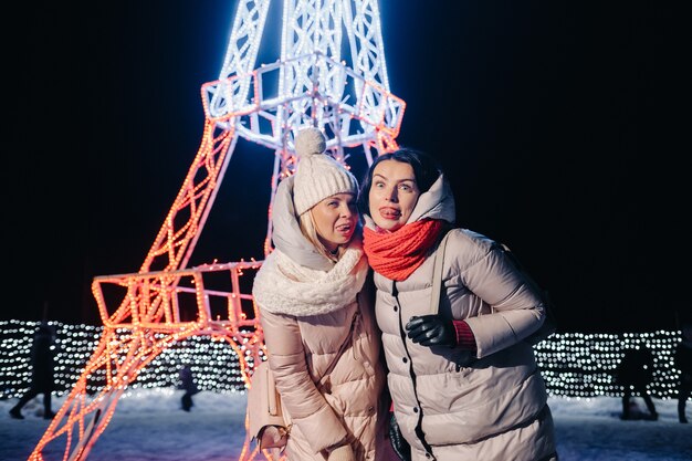 Photo deux filles en hiver avec les lumières du nouvel an brûlant dans la rue de noël