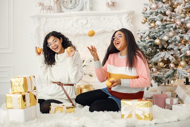 Deux filles indiennes à lunettes assis près de l'arbre de Noël