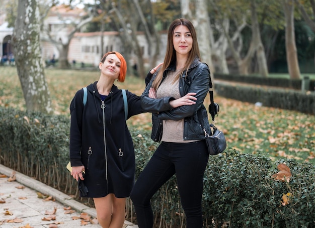 Deux filles - jeune couple de lesbiennes marchant dans un parc en automne et se moquant. Portrait d'un jeune couple de lesbiennes souriant s'embrassant tout en se tenant ensemble dans la rue de la ville