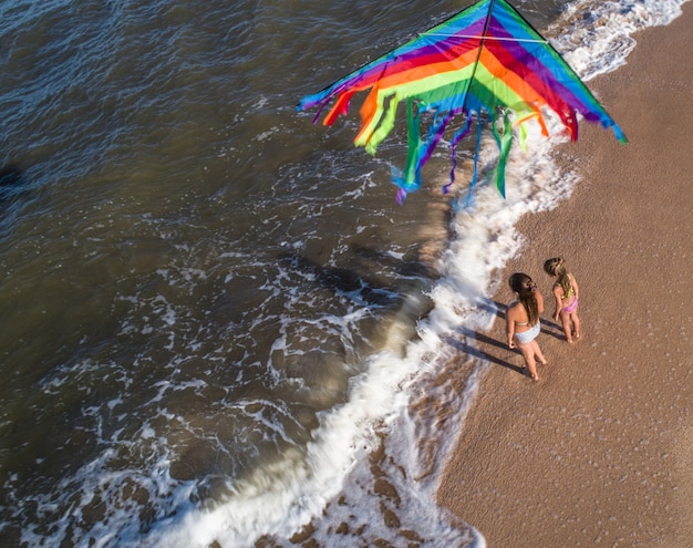 Deux filles jouent avec un cerf-volant au bord de la mer